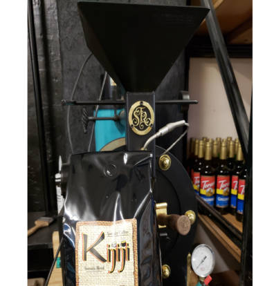 Bag of Kijiji Sumatra Blend Coffee in front of a coffee roaster